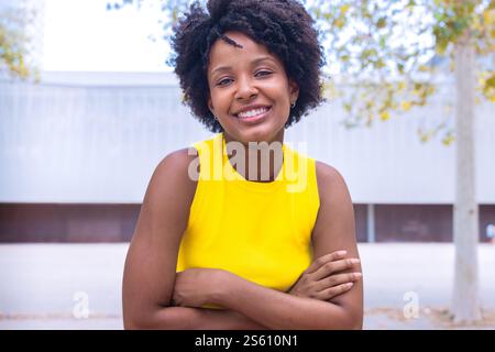 Lächelnde junge Frau in Gelb oben posiert draußen Stockfoto