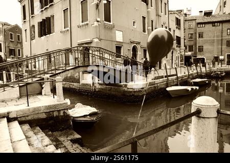 VENEDIG, ITALIEN - 14. FEBRUAR 2015: Ballon bei der Karnevalsparty am Kanalgeländer verloren. Historisches Foto von Sepia Stockfoto