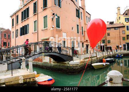 VENEDIG, ITALIEN - 14. FEBRUAR 2015: Roter Ballon verloren bei der Karnevalsparty am Kanalgeländer. Stockfoto