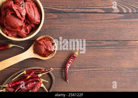 Traditionelle türkische Chili-Pfefferpaste in Schüssel oder Löffel mit getrockneten Paprika auf Holztisch, hausgemachte gesunde Lebensmittel Stockfoto