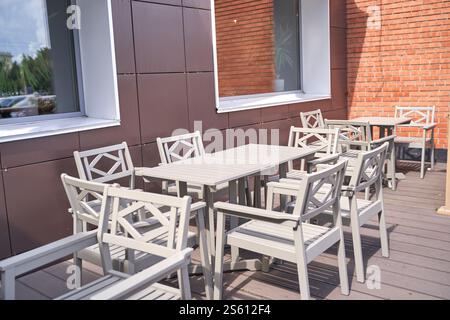 Außenterrasse mit hellgrauen Holzmöbeln und Backsteinmauern bei sonnigem Tageslicht. Stockfoto