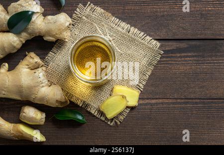 Glasflasche mit ätherischem Ingweröl und Ingwerwurzeln auf rustikalem hölzernem Hintergrund. Alternatin-Medizin. Zingiber officinale Stockfoto