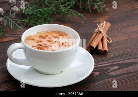 Weiße Tasse salep milky traditionelles Heißgetränk von Truthahn mit Zimtpulver und Stäbchen auf rustikalem Vintage Holztisch. Sahlep-Hintergrund Stockfoto