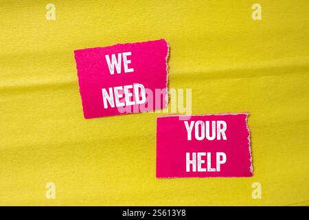 Wir brauchen Ihre Hilfe, geschrieben auf gerissenen rosa Papierstücken auf gelbem Hintergrund. Konzeptionell brauchen wir Ihr Hilfesymbol. Kopierbereich. Stockfoto