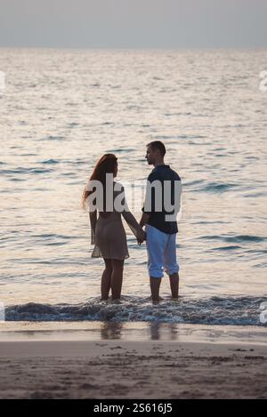 Ein Paar, das Hände an einem Sandstrand in Thailand hält Stockfoto