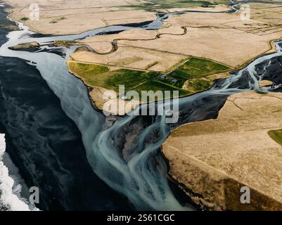Aus der Vogelperspektive eines Gletscherflusses, der auf einen schwarzen Sandstrand in Südisland trifft Stockfoto