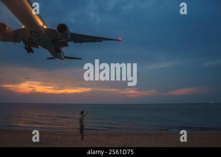 Flugzeug fliegt tief über Mai Khao Beach bei Sonnenuntergang in Phuket, Thailand Stockfoto