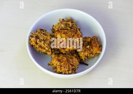 Knuspriges, knuspriges Pakora, serviert auf einer weißen Schüssel. Diese köstlichen frittierten Pommes frites sind ein beliebter Snack oder Vorspeise in Bangladesch, Indien und anderen Ländern Stockfoto