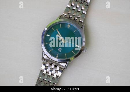 Nahaufnahme einer analogen Herrenarmbanduhr mit Edelstahlarmband und Datumsfunktion. Stockfoto
