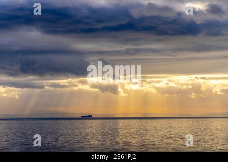 Sonnenstrahlen, die durch die dunklen Wolken auf einem Schiff in der adria ragen, erzeugen einen dramatischen Effekt Stockfoto