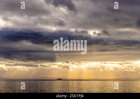 Sonnenstrahlen, die durch die dunklen Wolken auf einem Schiff in der adria ragen, erzeugen einen dramatischen Effekt Stockfoto