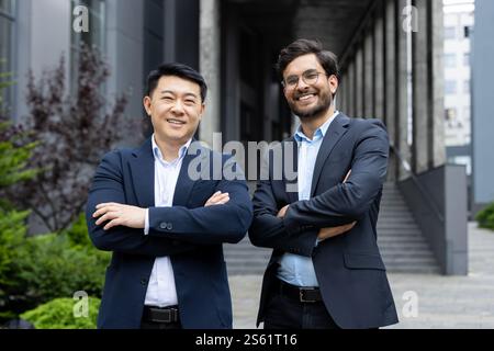 Porträt zweier erfolgreicher Geschäftsleute. Kollegen in Geschäftsanzügen lächeln und in die Kamera schauen, Männer vor dem Bürogebäude. Stockfoto