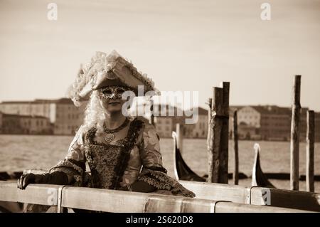 VENEDIG, ITALIEN - 16. FEBRUAR 2015: Maske auf dem Markusplatz (mit Blick auf die Insel San Giorgio Maggiore) während des Karnevals. Sepia-Foto Stockfoto