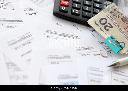 Polnisches Zloty-Geld PLN, Taschenrechner und Stift auf einer großen Menge polnischer PIT-, CIT- und Mehrwertsteuerformulare aus nächster Nähe. Buchhaltung, Bürokratie und Steuerzahler Stockfoto