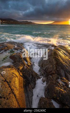 Wellen krachen über die Felsen am Nisabost Beach, Isle of Harris, Schottland, bei Sonnenuntergang Stockfoto