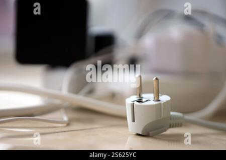 Überlastete Stromversorgungsplatinen. Steckdosenleisten mit verschiedenen Steckern auf weißem Boden. Konzept der Gefahr Gefahr Überlaststrom elektrisch. Stockfoto