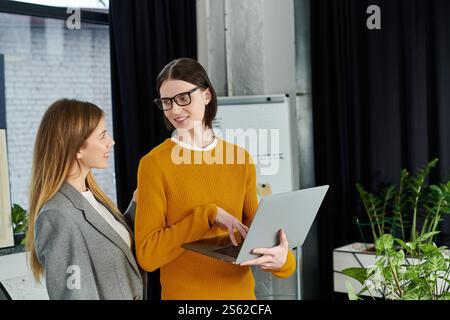 Zwei junge Menschen tauschen ihre Ideen aus, während sie nebeneinander in einer stilvollen Büroumgebung stehen. Stockfoto