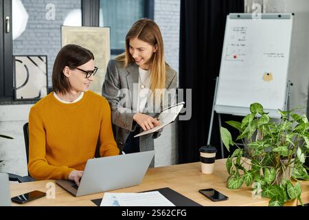 Zwei schicke Personen führen eine kreative Diskussion, während sie gemeinsam an einem Notebook arbeiten. Stockfoto