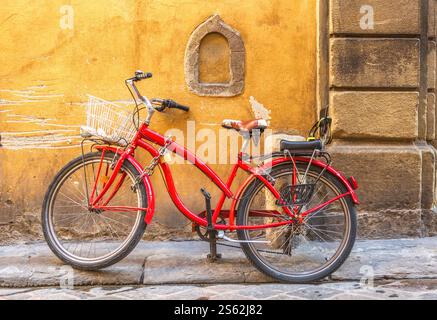 Ein rotes Fahrrad und ein Weinfenster in der Via delle Terme, einer historischen Straße der Altstadt von Florenz Stockfoto