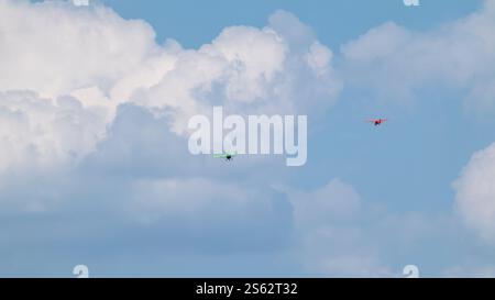 Grüne und rote Aeroprakt ukrainische Ultraleichtflugzeuge fliegen in bewölktem blauen Himmel Stockfoto