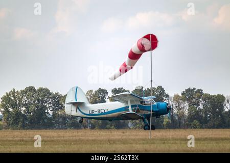 An-2 Passagierflugzeuge starten auf dem Graslandeplatz hinter Windsocken Stockfoto