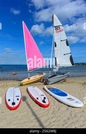 Segeljollen und Paddelbretter an einem Strand in Knoll Beach, Shell Bay, Studland, Dorset Stockfoto