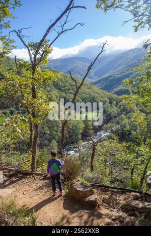 Der Junge beobachtet den Jerte River, der sich durch das Tal schlängelt. Naturschutzgebiet Garganta de los Infiernos, Extremadura, Spanien Stockfoto
