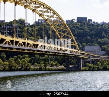 Pittsburgh, Pennsylvania, USA - 8. August 2023: Eine lebhafte gelbe Brücke verbindet den Fort Pitt Tunnel, umgeben von üppigem Grün. Stockfoto