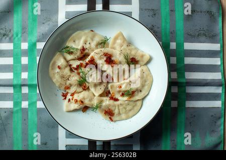 Varenyky oder Teigtaschen mit gebratenen Zwiebeln und Dill, serviert auf weißem Teller Stockfoto
