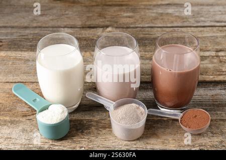 Verschiedene leckere Proteincocktails in Gläsern und Pudern auf Holztisch Stockfoto