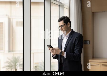 Junger arabischer Geschäftsmann mit Smartphone am Arbeitsplatz Stockfoto