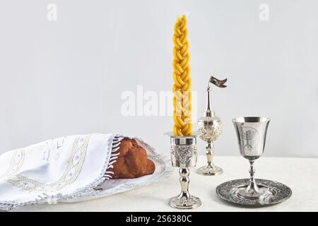 Shabbat-Tischeinstellung. Challah-Brot, geflochtene Kerze und silberne Kiddush-Tasse, Stockfoto