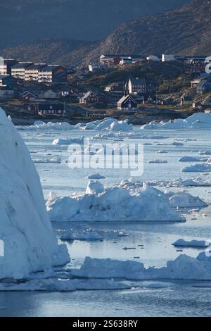 Eisberge schwimmen im Meer in der Nähe des Hafens von Ilulissat mit der Stadt Ilulissat im Hintergrund. Ilulissat. Disko Bay. Grönland Stockfoto