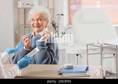 Seniorin mit Hörgerät, Arztbesuch in der Klinik Stockfoto