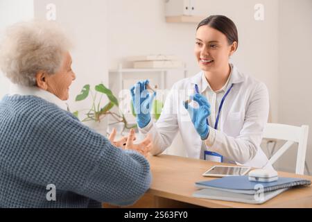 Ärztin zeigt Hörgeräte einer Seniorin in der Klinik Stockfoto