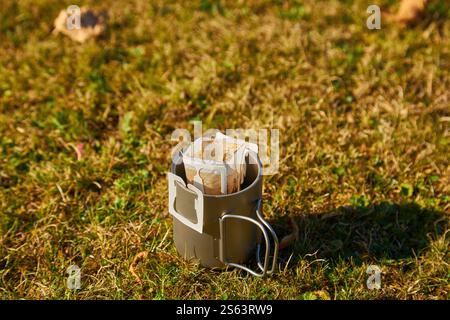 In den Herbstbergen wird eine Tasse transportablen Tropfkaffee zubereitet. Vor dem Hintergrund der wilden Natur Stockfoto
