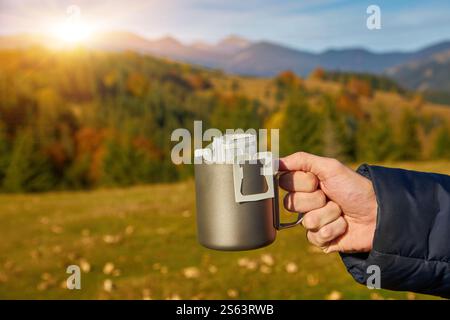 In den Herbstbergen wird eine Tasse transportablen Tropfkaffee zubereitet. Vor dem Hintergrund der wilden Natur Stockfoto