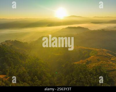 Aus der Vogelperspektive Ein atemberaubender Blick auf eine üppige, grüne Bergkette unter einem hellen, klaren blauen Himmel, mit Sonnenlicht, das die riesigen, rollenden Berge beleuchtet Stockfoto