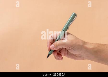 Mann Hand mit grünem Stift auf beigefarbenem Hintergrund Stockfoto