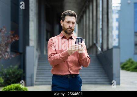 Ernsthaft nachdenklicher Mann denkt beim Lesen von E-Mails geht ein Geschäftsmann mit Smartphone in der Hand und nutzt die Messaging-App. Stockfoto