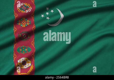 Die Flagge Turkmenistans ist auf einem Sportstoff mit vielen Falten abgebildet. Das Sportteam schwenkt Banner. Die Flagge Turkmenistans ist auf einem Sporttuch abgebildet Stockfoto