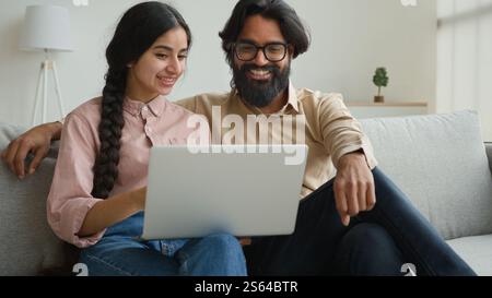 Arabian Indianerpaar auf Couch Sofa benutzen Computer Laptop Shopping online Internet Shop glückliche multirassische Frau Ehemann lächelnd schöne Kunden Frau Stockfoto