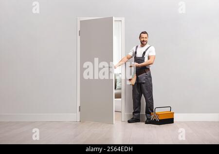 Ein Reparaturmann mit einem Werkzeugkasten, der eine Tür für eine Wohnung öffnet Stockfoto