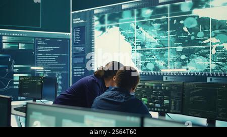 Hacker aus der Regierung, die fortschrittliche Software zum Schutz vor Cyberbedrohungen einsetzen, arbeiten im Team. Spezialisten für Cybersicherheit, Daten- und Netzwerkschutz vereinen Kräfte in High-Tech-Büros. Kamera B.. Stockfoto