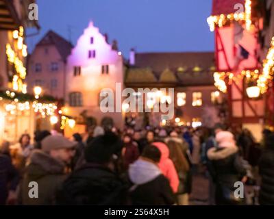 Ein lebendiges und festliches Bild mit verschwommenem Hintergrund, das eine farbenfrohe Unschärfe des Weihnachtsmarktes in Colmar, Frankreich, zeigt Stockfoto