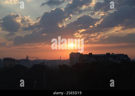 Wunderschöner Sonnenaufgang mit warmem orangenem Sonnenlicht und Sonnenstrahlen durch den bewölkten blauen Himmel. Wunderschöner Sonnenaufgang mit warmem orangenem Sonnenlicht und Sonnenstrahlen durch den blauen Himmel Stockfoto