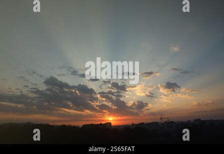 Wunderschöner Sonnenaufgang mit warmem orangenem Sonnenlicht und Sonnenstrahlen durch den bewölkten blauen Himmel. Wunderschöner Sonnenaufgang mit warmem orangenem Sonnenlicht und Sonnenstrahlen durch den blauen Himmel Stockfoto