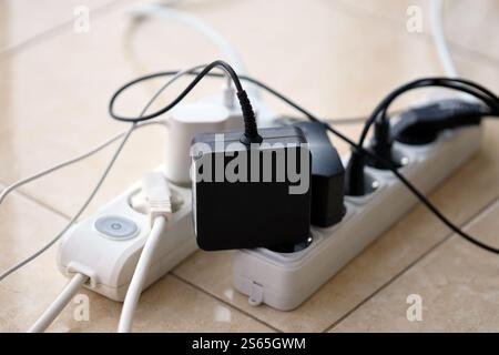 Überlastete Stromversorgungsplatinen. Steckdosenleisten mit verschiedenen Steckern auf weißem Boden. Konzept der Gefahr Gefahr Überlaststrom elektrisch. Stockfoto