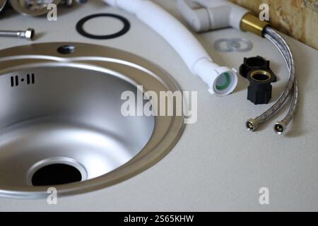Klempner Werkzeuge und Wasserhahn bereit für die Installation in der Nähe des Waschbeckens auf der Arbeitsplatte in der Küche. Anschlüsse für die Installation des Wasserhahns für den Stockfoto