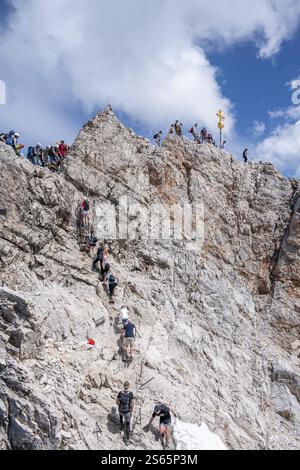 Touristen stellen sich an den Gipfel der Zugspitze, Gipfel mit goldenem Gipfelkreuz, Übertourismus, Wettersteinkette, Bayern, Deutschland, Europa Stockfoto
